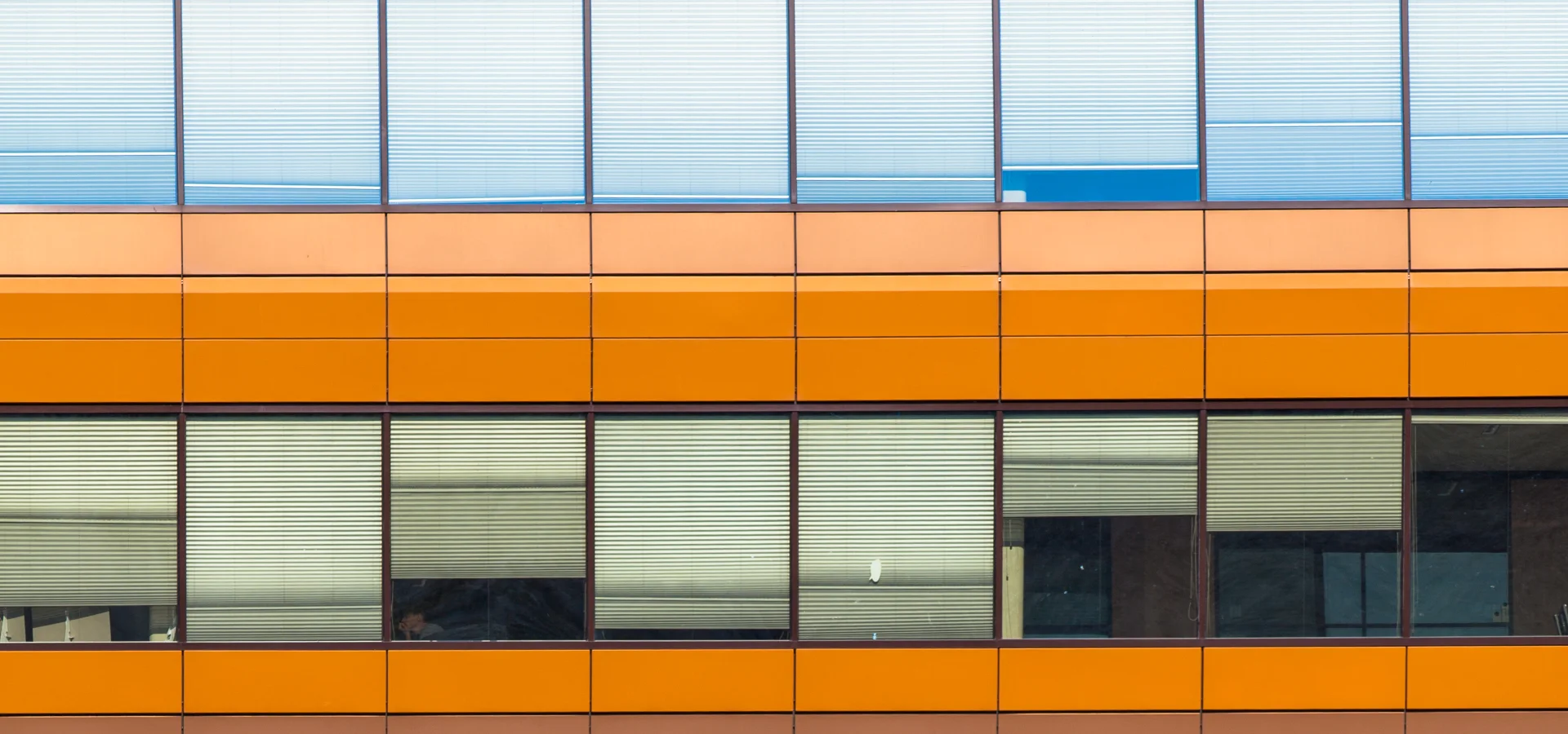 Blau-orange gegliederte Fassade als architektonisches Ordnungsmotiv